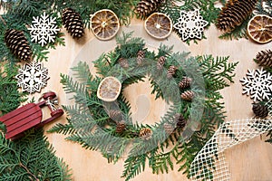 Preparation for Christmas holiday. Christmas composition of wreath, decor, dry orange, sleigh and snowflakes. Top view and copy sp