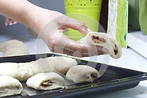 Preparation of cinnamon rolls. A woman puts buns of buns on a baking tray.