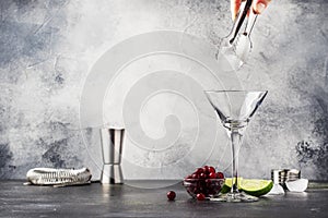 Preparation Classic alcoholic cocktail cosmpolitan with vodka, liqueur, cranberry juice, lime, ice and orange zest, gray bar