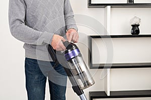 Preparation for Cleaning: Man with Cordless Vacuum in White Room