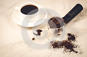 preparation of coffee/holder filled with ground coffee and a white cup