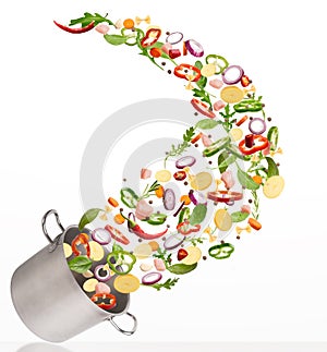 Fresh vegetables flying into steel pot, isolated on white background