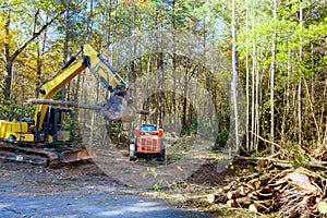 In preparation for constructing a new home builder uproots trees from forest with tractor