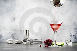 Preparation Classic alcoholic cocktail cosmpolitan with vodka, liqueur, cranberry juice, lime, ice and orange zest, gray bar