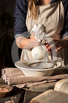 Preparation of cottage cheese - woman straining the milk through a cheesecloth