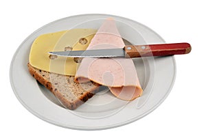 Preparation of a croque-monsieur with a slice of sandwich bread, ham and Emmental cheese on a plate with a knife on a white backgr