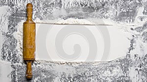 Preparation of the dough. The rolling pin with flour on a stone background.