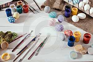 Preparation for Easter. Colorful handmade Easter eggs, paint, brushes on a white wooden background tabel