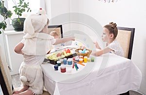 Preparation for Easter: the elder sister teaches the younger brother to paint eggs for Easter.