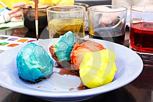 preparation for Easter. Glasses with colored paint and white eggs with a blue plate