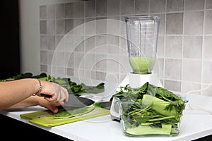 Preparation of green juice in the kitchen with blender nopales are cut on chopping board as an ingredient in a nutritious and heal