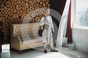 Preparation of the groom for the wedding day. Man dresses a white shirt in the morning in the studio with a wooden