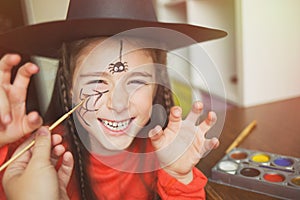 Preparation for Halloween. child in a witch outfit doing face painting. cute spider. idea of simple suit, diy