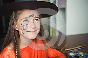 Preparation for Halloween. child in a witch outfit doing face painting. cute spider. idea of simple suit, diy