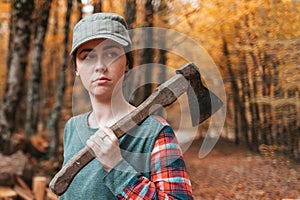 Preparation for the heating season. A young woman stands with an axe on her shoulder and looks gravely away. In the background, a photo