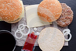 Preparation of homemade burger on black background, flat lay