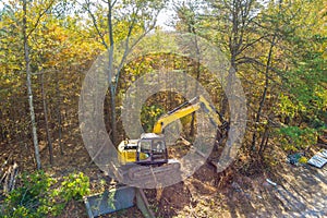 Preparation of land for construction, use of an excavator tractor to uproot trees make space for construction of a house photo