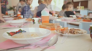 Preparation for a lunch break in the kindergarten. Children sit down at the table with cooked food. The Russian