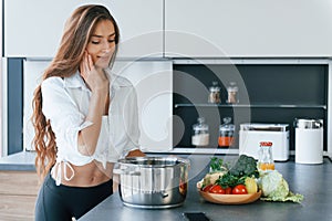 Preparation of meal in bowl. Young european woman is indoors at kitchen indoors with healthy food