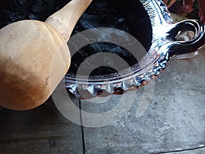 Preparation of Mexican Mole Rojo dish made with chili peppers, spices, chocolate, tortillas and ground bread in clay pot with wood