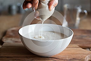 Preparation of nut milk - straining the milk through a milk bag