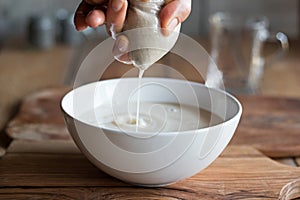 Preparation of nut milk - straining the milk through a milk bag photo