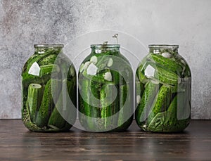 Preparation for pickling cucumbers. Preservation. Canned pickled cucumbers in jars on wood table.