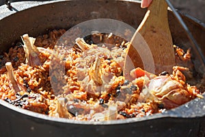 Preparation of pilaf on fire. Tourist bowler with food on bonfire, cooking in the hike, outdoor.