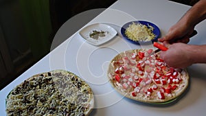 Preparation of pizza. A man chopped crab sticks for pizza. Next to the table is a pizza, ready for cooking and other ingredients.