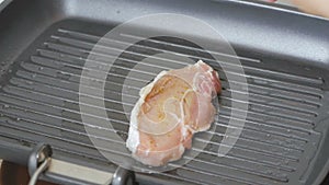 Preparation of pork chop in the pan is a grill. The meat is fried on a ribbed surface.
