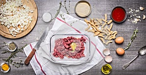 Preparation of raw minced meat balls with egg breadcrumbs eggs paste tomato sauce, garlic herb seasoning knife sliced onions