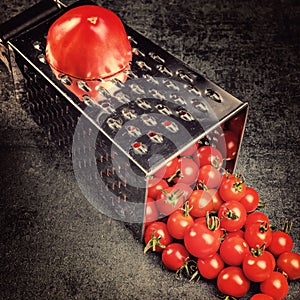 Preparation recipe tomato juice. Large tomato and old grater down to small grape cherry tomatoes on retro vintage rustic gray sto