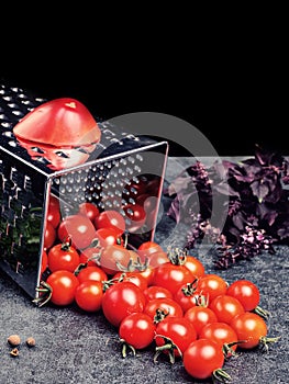 Preparation recipe tomato juice. Large tomato and old grater down to small grape cherry tomatoes on retro vintage rustic gray ston
