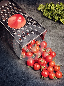 Preparation recipe tomato juice. Large tomato and old grater down to small grape cherry tomatoes on retro vintage rustic gray ston