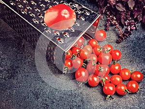 Preparation recipe tomato juice. Large tomato and old grater down to small grape cherry tomatoes on retro vintage rustic gray ston