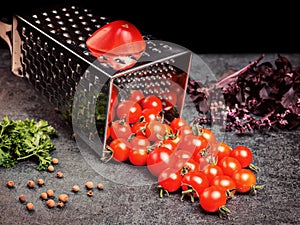 Preparation recipe tomato juice. Large tomato and old grater down to small grape cherry tomatoes on retro vintage rustic gray ston