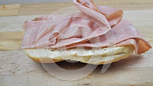 Preparation of a sandwich with mortadella, close-up view, hands working with bread and salami.