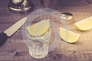 Preparation of shot with a lime in a shaker/preparation of shot with a lime in a shaker on a wooden background. selective focus