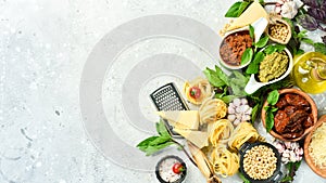 Preparation of spaghetti: pesto sauce, pasta, basil, parmesan and nuts, olive oil. On a concrete background.