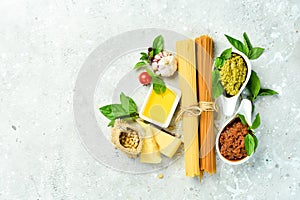 Preparation of spaghetti: pesto sauce, pasta, basil, parmesan and nuts, olive oil. On a concrete background.