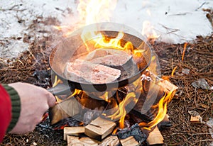 Preparation of steak from red fish in winter in the forest at the stake