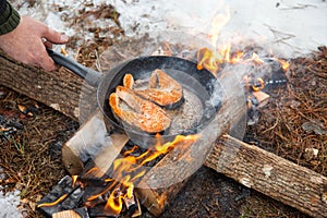 Preparation of steak from red fish in winter in the forest at the stake