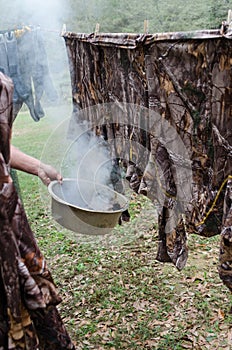 Preparation to hunt by smoking hunting clothes to mask human scent.