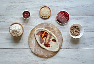 Preparation of traditional Arabic pizza manaqish with meat.