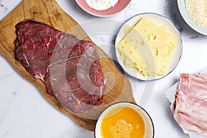 Preparation of traditional Milanese escalope with flour, egg, breadcrumbs, cheese and ham