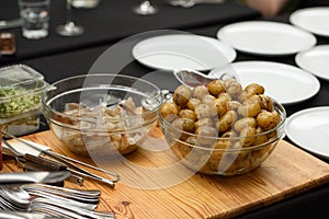 preparation of traditional spanish tapas served on plates on black table background. Patatas Bravas with Gambas Ajillo