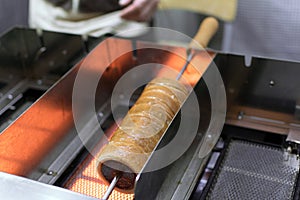 Preparation of the traditional Trdelnik a kind of spit cake made from rolled dough wrapped around a stick, grilled