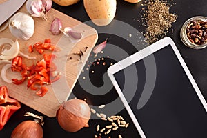 Preparation of vegetables on black wooden table with tablet top