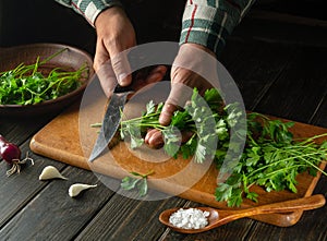 Preparation of a vitamin salad of parsley and onions by the hands of a cook on the kitchen table. The idea of a vegetarian diet