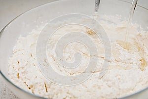 Preparation of the yeast dough. Adding water to the dough in the glass bowl